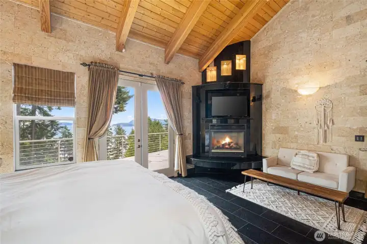 The second primary suite offers vaulted ceilings, private deck access, a propane fireplace, and partial water views.