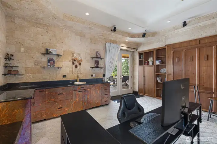 Lower-level guest and media area includes a wet bar, custom cabinetry, built-ins, and direct access to the outdoor patio.