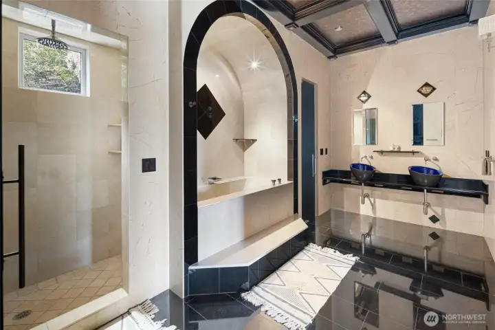 Spacious lower-level bathroom offers a walk-in shower, soaking tub, dual vessel sinks, and extensive stone and tile finishes.