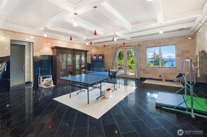 Generous bonus room with coffered ceilings, polished tile flooring, water views, and deck access provides space for games and recreation.