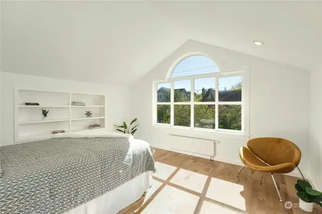 Second top floor bedroom features an arched window, vaulted ceiling and built-in shelves.