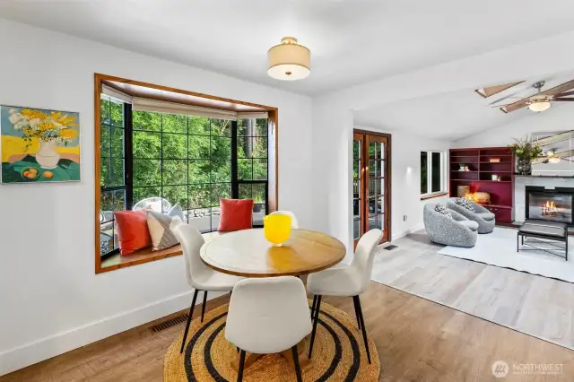 The eating nook with bench seat overlooks a large rec room.