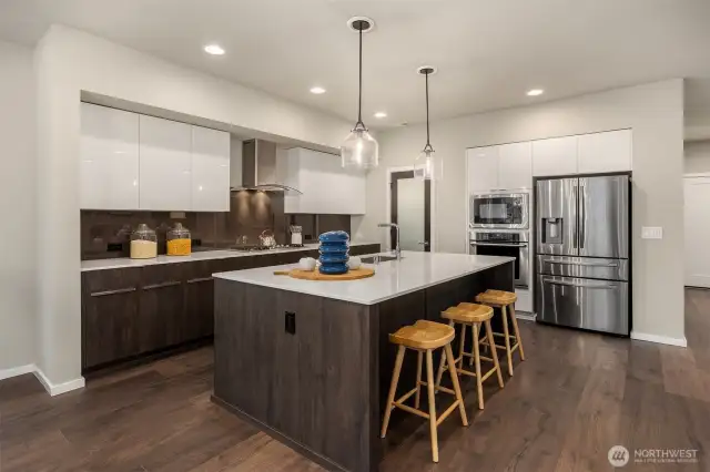 Bold and contemporary, the dual cabinetry; warm wood lowers and shiny white upper and stainless fridge and ovens frames.
