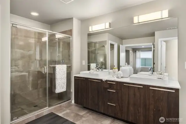 The spa-like Primary bath with tiled shower surround, tiled floors, and double vanities.
