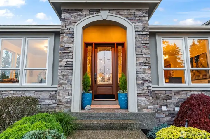 A warm, welcoming entry framed by stonework and custom glass doors, reflecting Zetterberg’s hallmark craftsmanship.