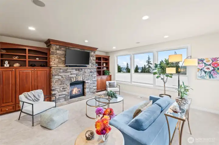 View-rich living area featuring a stone mantel, built-in cabinetry, and serene natural light—perfect for relaxed everyday living.