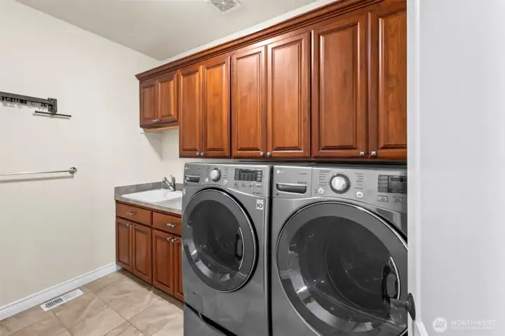 Main-floor laundry with extensive cabinetry, utility sink, and LG washer/dryer—organized and functional.