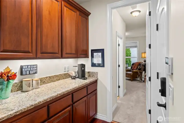 A second Butler’s pantry/coffee bar connecting kitchen and secondary suite hallway, adding convenience to the main level.  The door to the garage is opposite the bar.