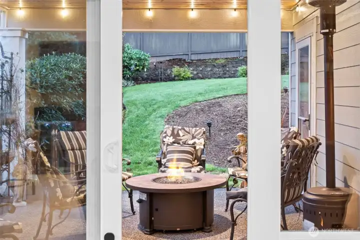 Covered patio with firepit, creating a cozy year-round outdoor living space overlooking peaceful, terraced gardens.