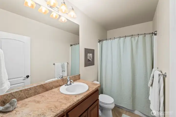 Full guest bath with classic tile and warm finishes.  One of 2 full baths conveniently located for lower-level bedrooms.