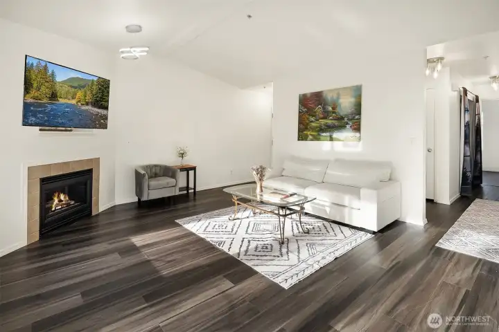 A spacious living room with laminate wood flooring, gas fireplace, and a cut out for TV above the FP