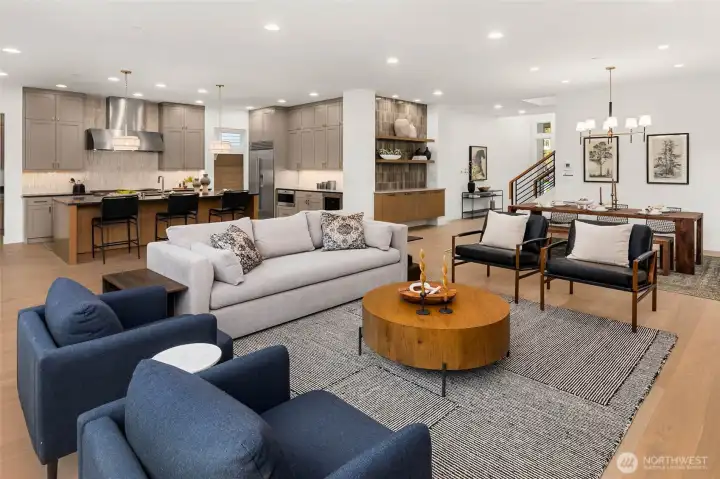 Open concept living with 10 foot ceilings, wide plank hardwood flooring. Custom designed floating buffet cabinet with slab top, full height designer tile backsplash, and floating shelves eloquently supports the dining area