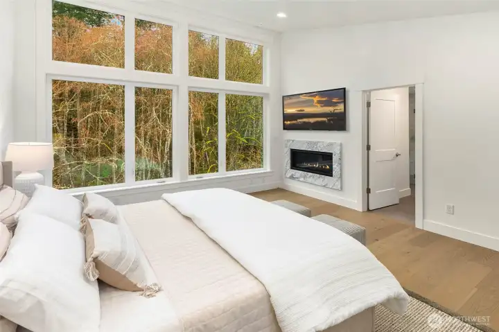 Stunning and Serene primary suite with window walls and contemporary fireplace with tile surround