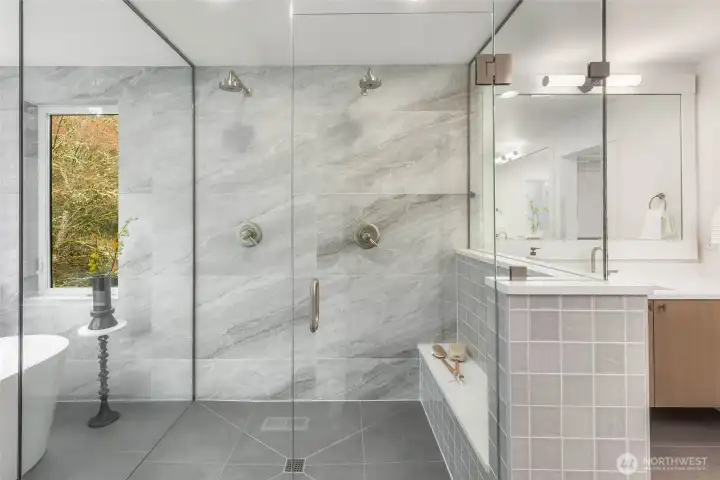 Gorgeous walk in shower with custom bench duel heads, designer selected tile, and frameless glass surround