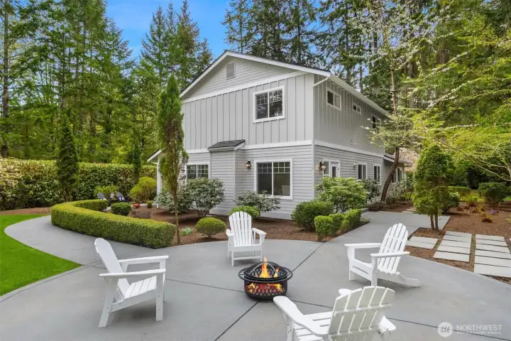 A private outdoor retreat designed for effortless entertaining—where sunlit patios, open sky, and a peaceful, wooded backdrop create the perfect setting for gathering, dining, and quiet evenings by the fire.