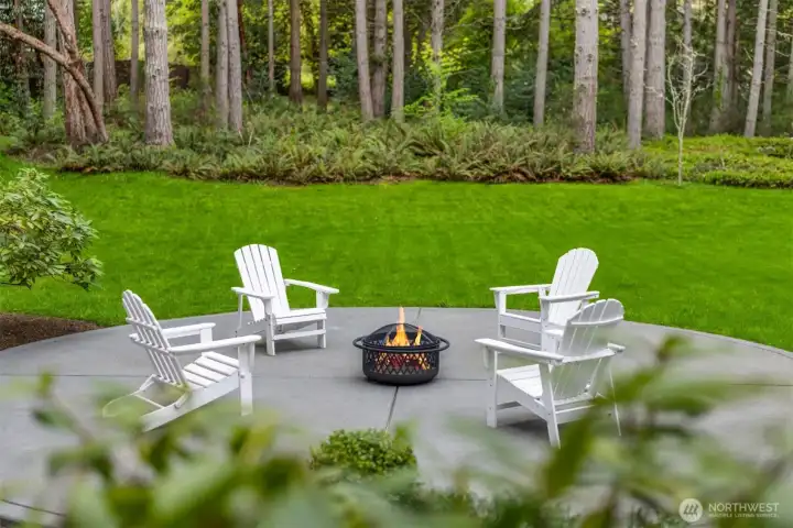 A quiet moment at the edge of the trees—where a simple firepit and Adirondack chairs invite slow evenings, conversation, and a deeper connection to Bainbridge’s natural landscape.