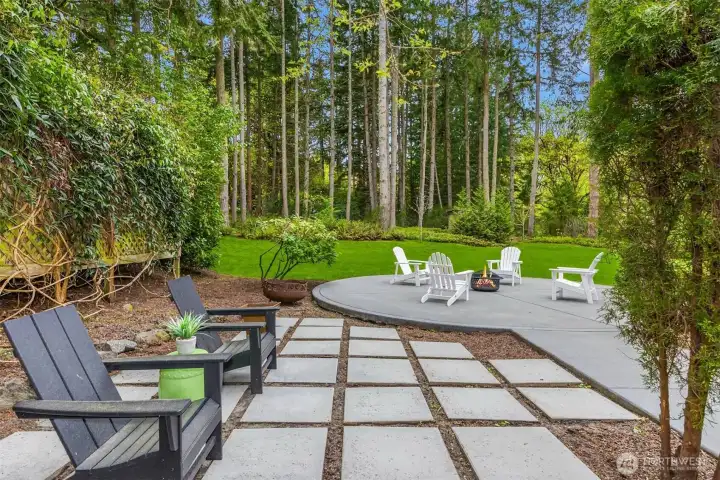 A thoughtfully designed outdoor living space—clean lines, defined zones, and seamless flow between dining, lounging, and fireside gathering, all set within a private, natural backdrop.