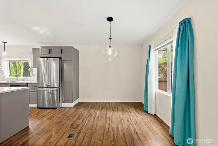 Open dining area adjacent to kitchen with updated lighting and backyard views