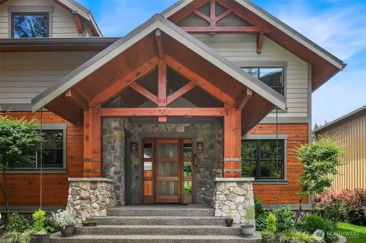 Exceptional architectural curb appeal greets you at the main entry, featuring a monumental timber frame portico with natural stone pillars, all-cedar exterior siding, and custom rain chains framing the magnificent old-growth cedar entrance.