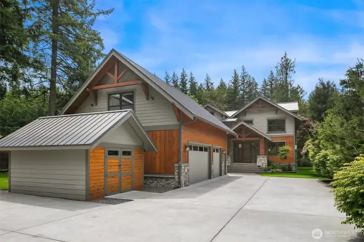 Sprawling front grounds feature a custom concrete driveway leading to the massive 1,675 SF detached 3-car garage—complete with a lower workshop, half bath, and independent 800 SF luxury living space upstairs—alongside a matching 12’x14’ powered storage shed.