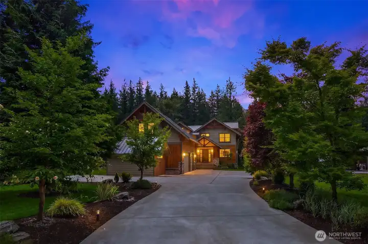 An enchanting evening approach showcases the fully automated, low-voltage landscape and driveway lighting system. This pristine, gated-ready concrete entrance guides you home to the ultimate private alpine sanctuary.