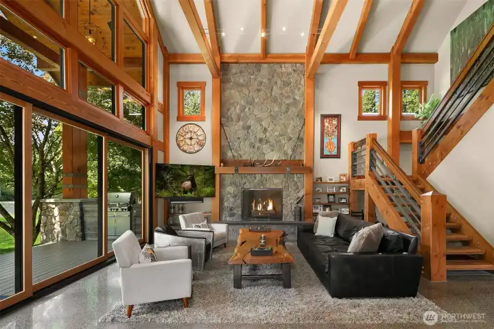 The dramatic focal point of the main living space: a monumental 8-foot-wide natural rock wall fireplace stretching all the way to the vaulted ceiling. Features a convenient gas starter, a custom old-growth cedar mantle, and bespoke artisan metal swinging doors.