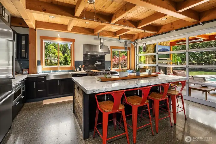 A chef’s dream workspace boasting custom dark-slab cabinetry, under-cabinet lighting, a built-in microwave drawer, and an industrial-scale layout tailored for high-volume entertaining.