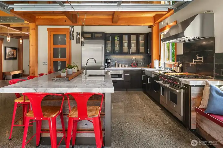 A spectacular culinary viewpoint. Stand at the professional Wolf range and enjoy direct sightlines through the open-air garage door to the covered patio and the peaceful flowing waters of the Middle Fork River.