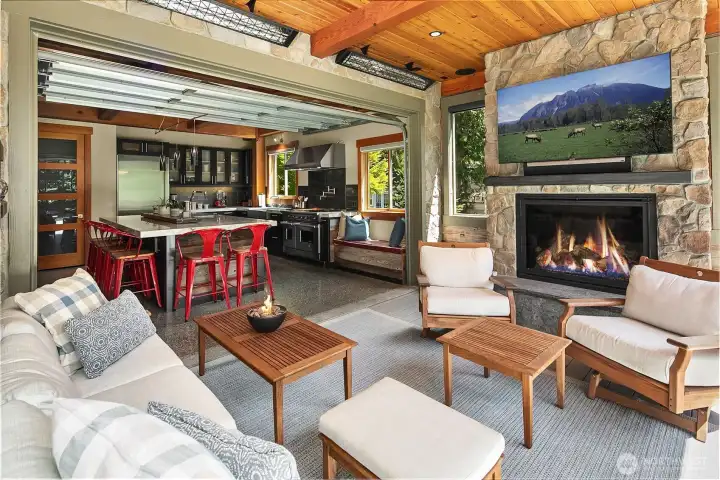 True indoor-outdoor harmony defined. Looking back from the heated outdoor lounge through the open garage door reveals the seamless transition into the main kitchen, creating a massive, cohesive entertaining pavilion.