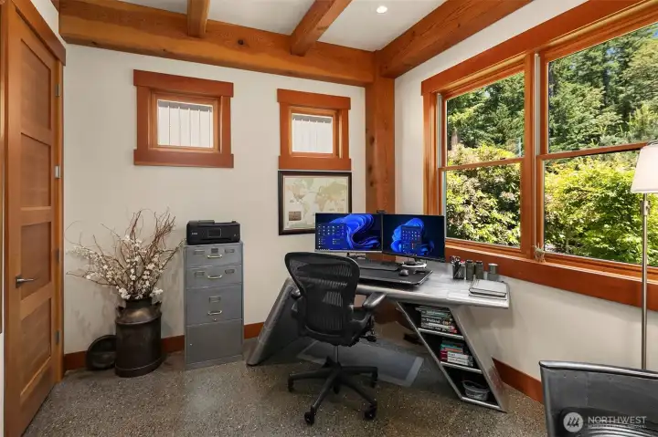 An inspiring executive home office. Features custom timber accents, radiant-heated polished concrete floors, and oversized windows that frame serene, private views of the surrounding native greenery.