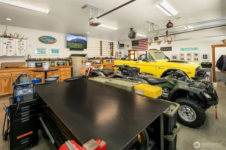 The ultimate heated showroom garage and hobbyist workshop. Meticulously finished with commercial-grade lighting, a massive heavy-duty fabrication table, extensive built-in tool cabinetry, and ample space for classic cars, ATVs, and outdoor gear.