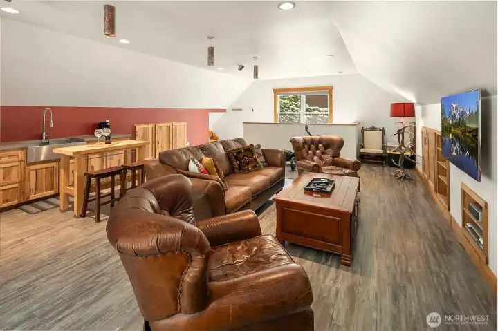 The spectacular luxury living space located above the garage. This fully self-contained accessory dwelling unit (ADU) features vaulted ceilings, rich wood-plank floors, a spacious media lounge, and a premium kitchenette with a concrete counter and stainless steel farmhouse sink.