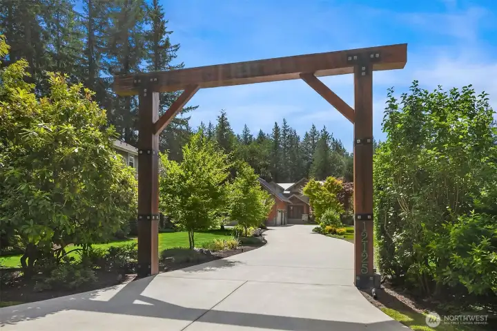 An unforgettable arrival. A monumental timber-framed entry arbor spans the estate's sweeping concrete driveway, setting an immediate tone of Pacific Northwest luxury and ultimate privacy.