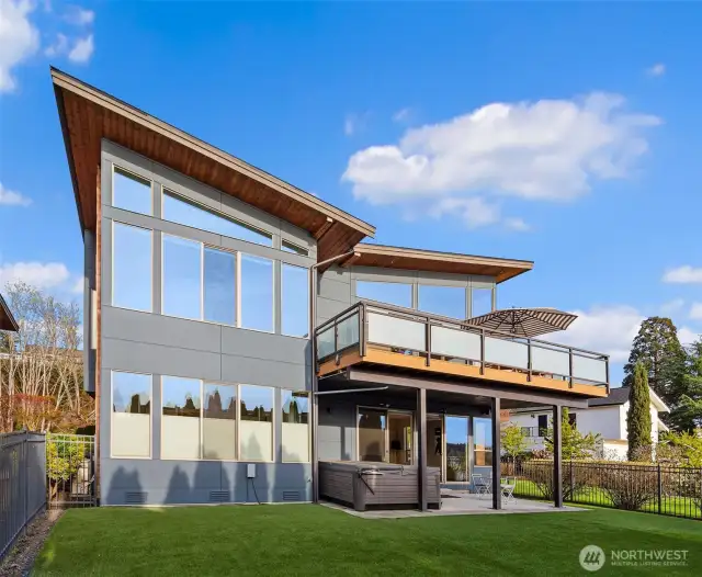 Water side of the home. Upper outside living area, lower covered patio w/ hot tub and fully fenced yard.