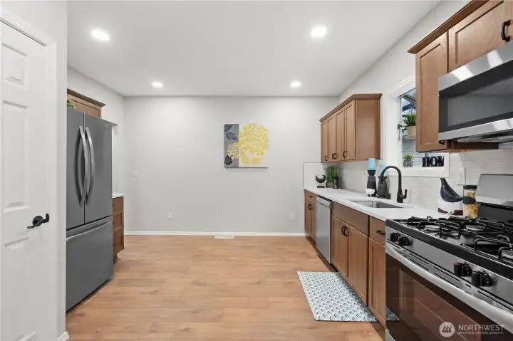 View entering into the Kitchen w/New Cabinets, Stainless Steel Appliances w/Gas Range and Over the Range Microwave. French Door Fridge w/Lower Freezer. In the Closet you'll find the New Gas Water Heater and Pantry Space.