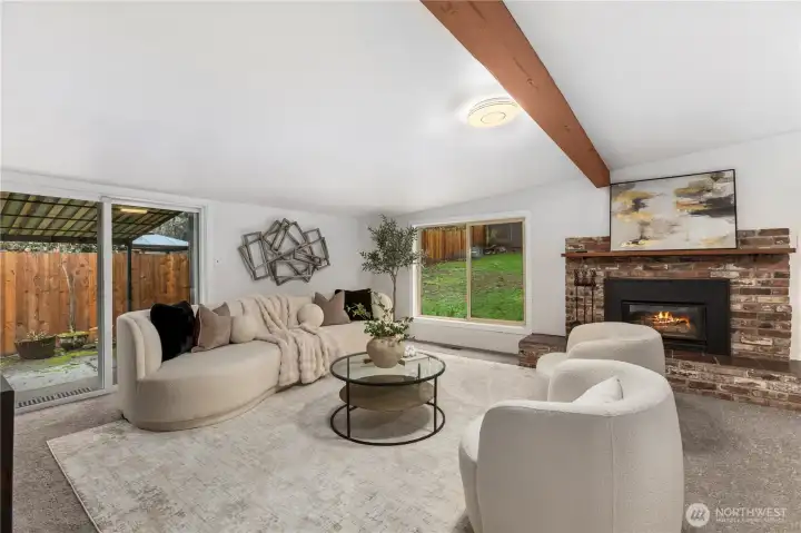 Beyond the kitchen is the heart of the home: a spacious, open, second living and dining space featuring exposed wood beams, a cozy gas fireplace, and easy access to the backyard