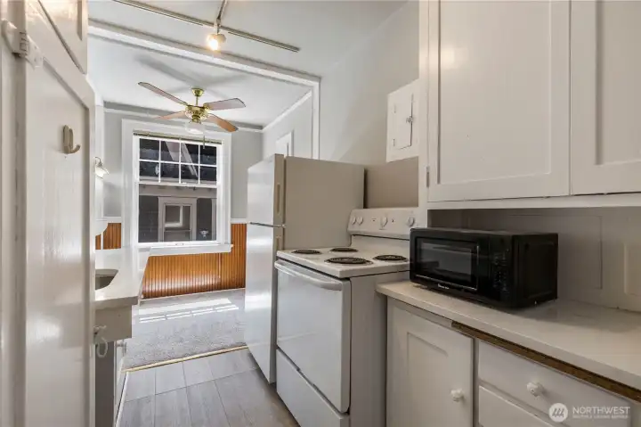 Second view of kitchen with new painted cabinets to match appliances new quartz counter under microwave and new vinyl planked flooring matching updated colors.  There is also new track over head lighting and second ceiling fan above eat in kitchen.  Come look at this before its gone