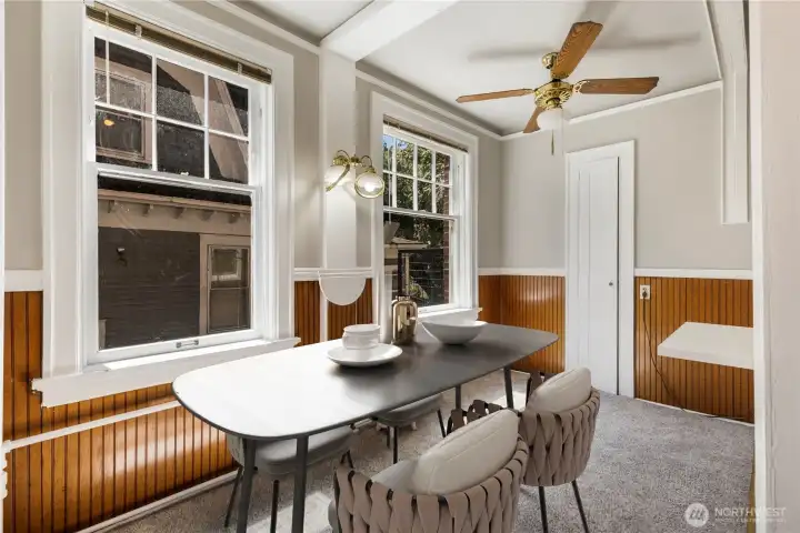 Virtually stage eat in kitchen dining room surrounded by wood colored wainscotting with views outside of city scapes.  There is also pantry storage also