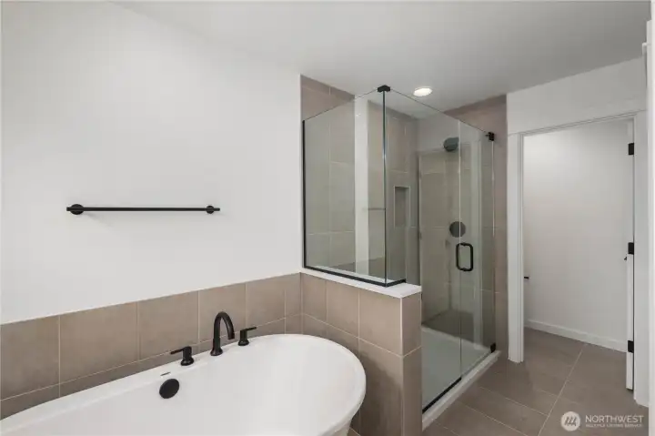 Primary Bath – Tub & Shower:  This angle highlights the pairing of a freestanding soaking tub with a spacious glass-enclosed shower, creating a balanced mix of relaxation and efficiency. The neutral tile palette adds warmth and continuity throughout the room. Located in Bothell’s Canyon Park micro-area, the primary bath complements a lifestyle surrounded by parks, everyday amenities, and quick access to major commuting routes. Its clean, modern finishes elevate daily routines with a quiet sense of luxury.    These photos are from Lot 5 at Gooden Hollow, which is the same floorplan, but a different home than listed here. However, other homes in the community will have changes, so all photos, renderings, site maps, and floorplans are for visualization purposes only. Plans, colors, building orientation, finishes, home outlook, and other details can and WILL vary.