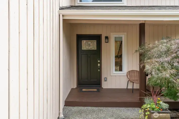 elcoming entry framed by mature landscaping and a level front yard