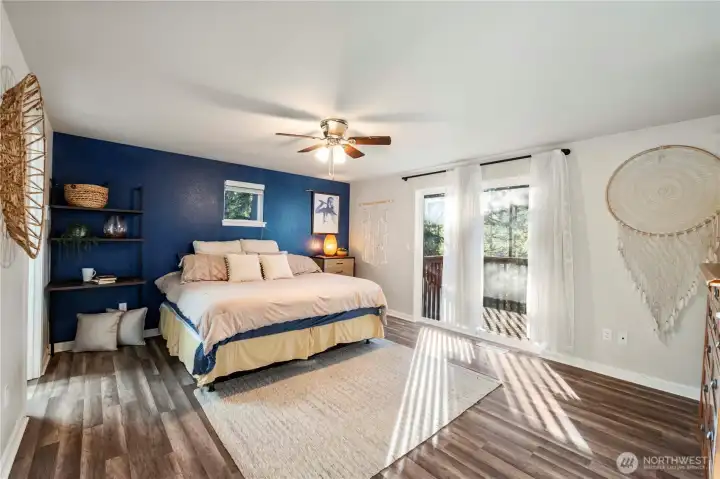 The primary bedroom is HUGE and offers a large slider and deck for enjoying the views. The decorative ceiling fan light circulates the fresh air and cooling A/C