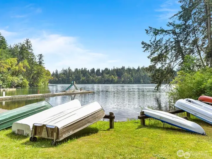 Summer view of the lake & spots to stow your boat & kayaks. The swim area offers a large dock and slide. There are a few beach areas to enjoy in the community