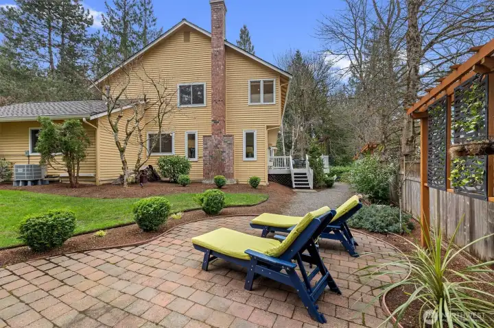 Fully fenced yard with grass play area and pavers for lounging
