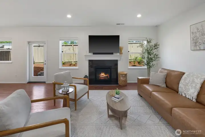Wide open living room with a gas fireplace covered in englneered hardwood flooring.