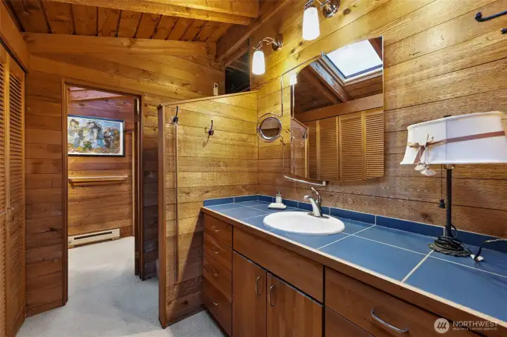 A primary bathroom with a linen closet and an abundance of closets for clothes to the left of this photo.