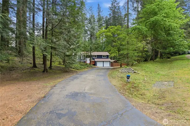 A long private driveway welcomes you home, leading to a peaceful retreat surrounded by lush greenery and mature trees.