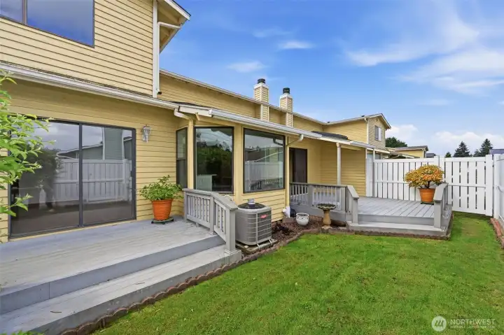 This backyard view shows the dual decks, one off the dining room, one off the main floor primary suite.