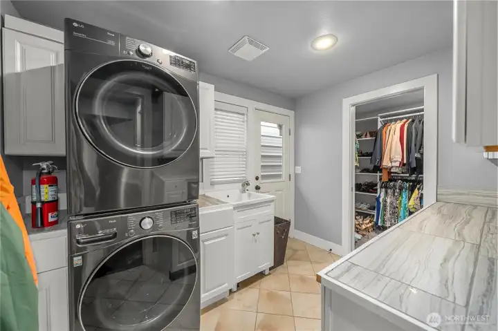 Convenient laundry room with ample counters, storage and wash sink.