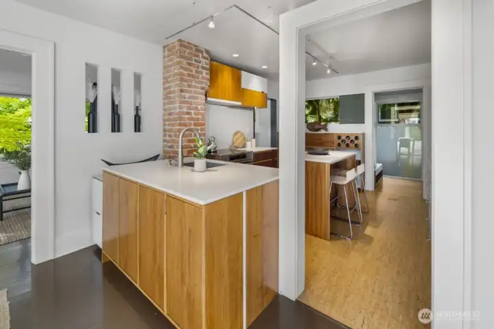 Streamlined kitchen with central prep island, brick detail, and adjacent breakfast bar for casual meals.