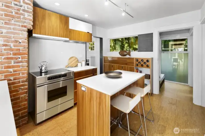 Kitchen hub with seating island, wine storage, and easy flow to nook and outdoor access